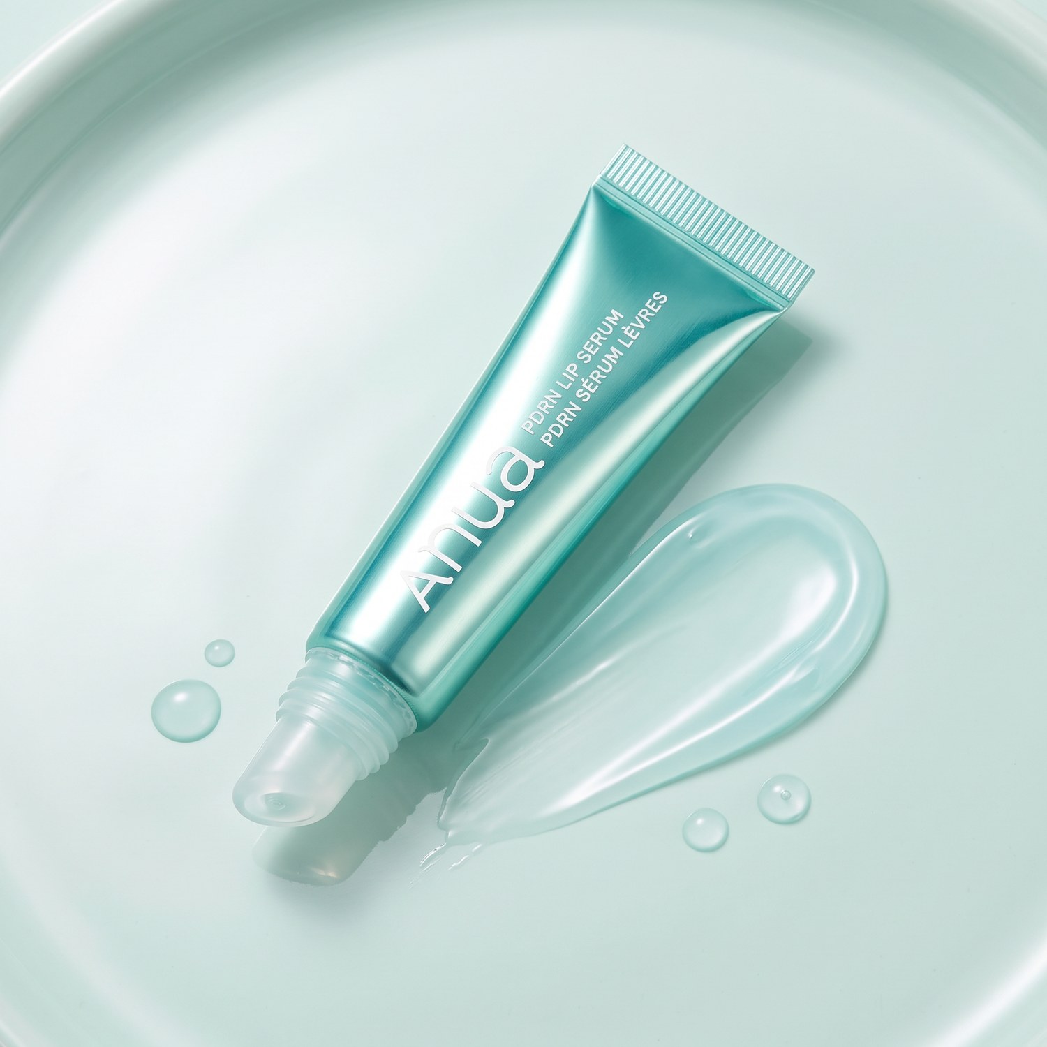 Anua PDRN Lip Serum con swatch de gloss sobre fondo menta